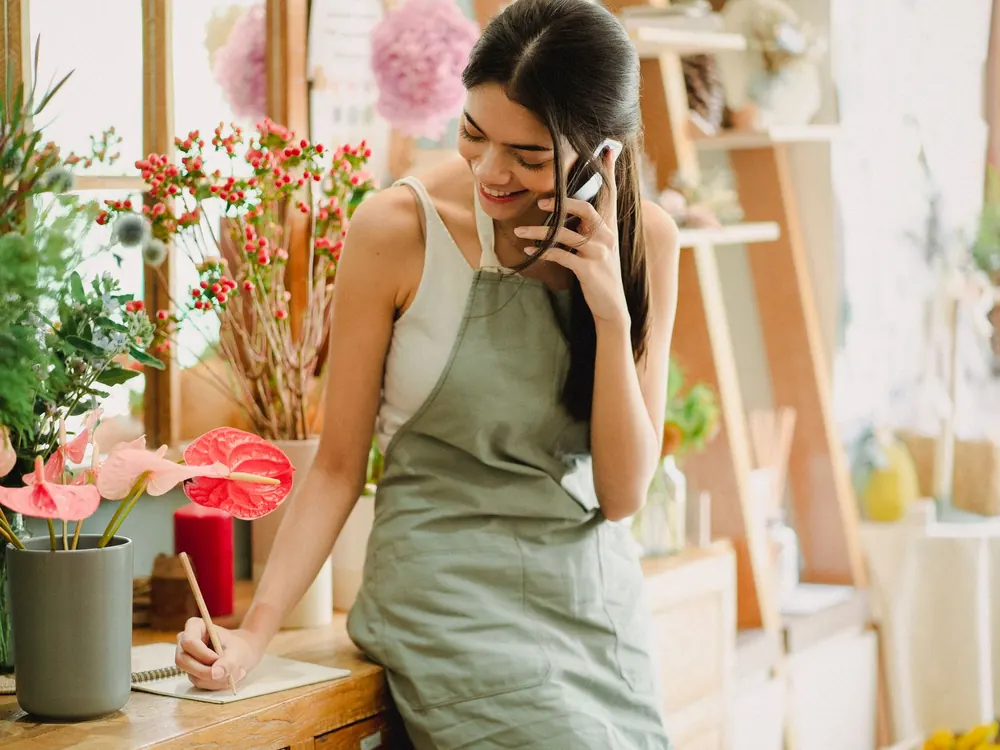 Emprendedora anota un pedido por teléfono en su tienda