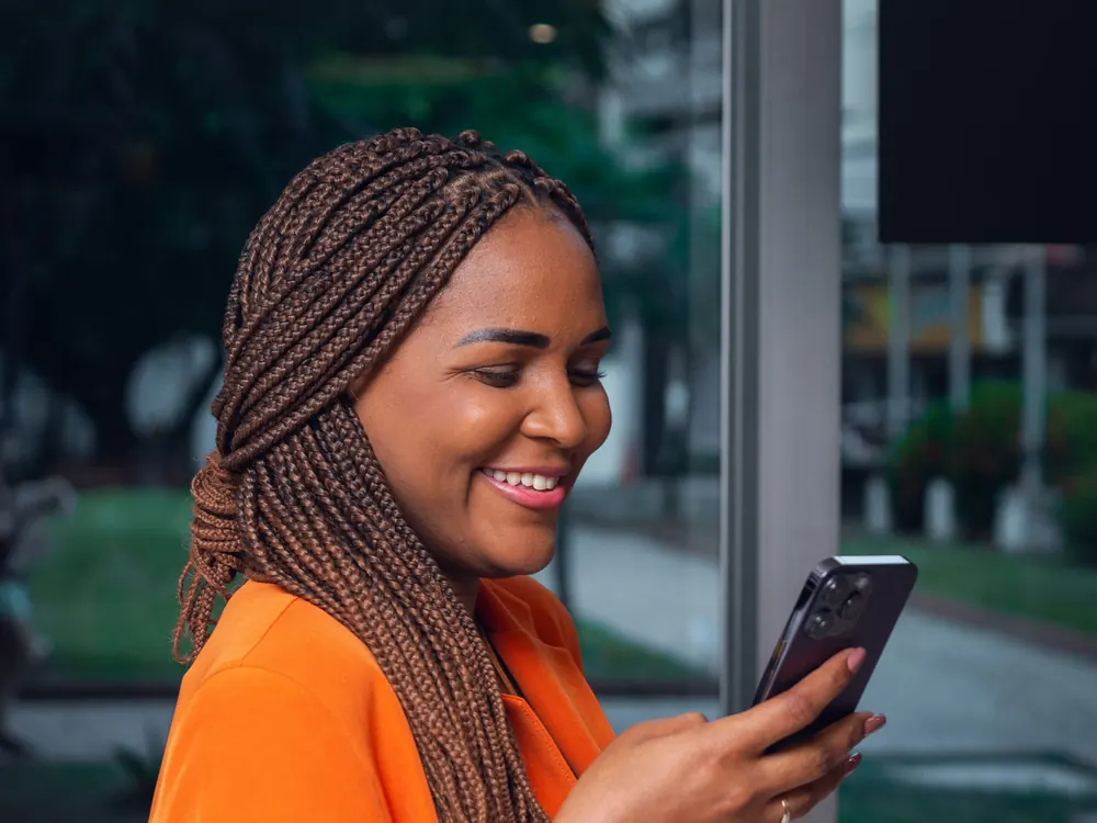 Emprendedora sonríe mientras revisa su cuenta en el celular