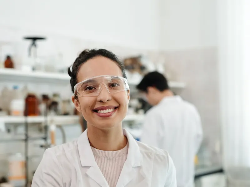Laboratorista con delantal blanco sonríe en su laboratorio